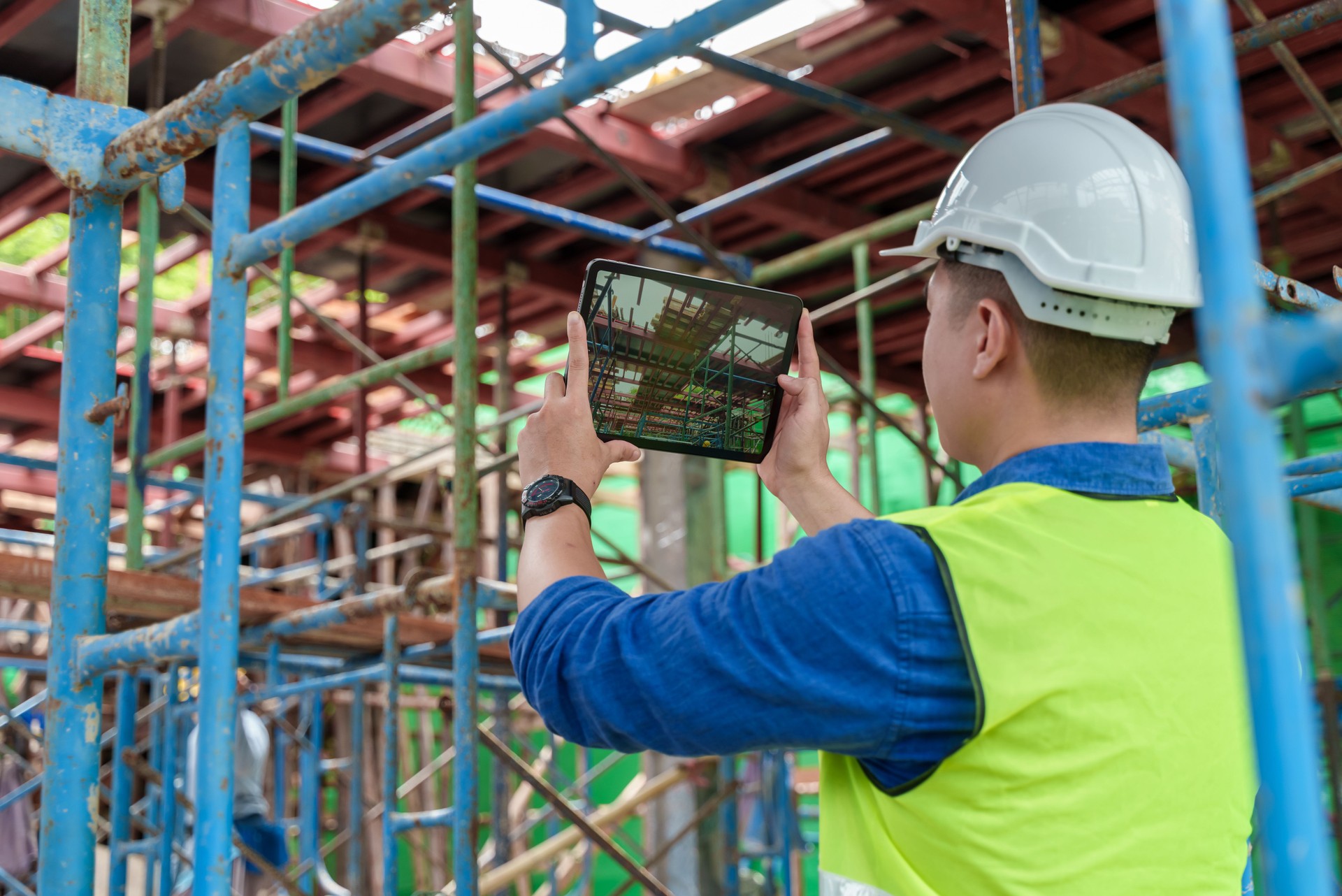 Young Asian construction worker using tablet while working at construction site.